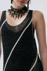 Vestido largo de punto calado negro con lurex y rayas diagonales blancas. Tiene escote redondo y flecos en el ruedo.