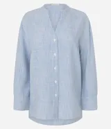 Camisa oversized de Marfinno confeccionada en viscolino con estampado de rayas celestes y blancas. Presenta cuello mao, escote en V con abotonado frontal, mangas largas con puños anchos y bajo redondeado.