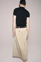 Top negro de punto fino con cuello polo, manga corta, cierre frontal de botones y un bolsillo de parche en el pecho.