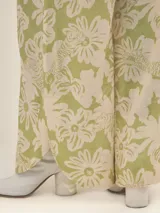 Pantalón ancho con estampado floral en tonos verde y blanco, con pinzas en el frente, bolsillos laterales y elástico en la cintura.