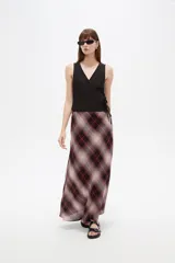 Musculosa de algodón sin mangas, de corte cruzado con cuello en V y diseño holgado, color blanco con estampado de lunares bordó y lazo lateral para ajustar.