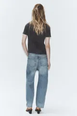 Jeans de tiro medio con corte cropped y diseño de costuras torcidas. Presenta trabillas en la cintura, cinco bolsillos clásicos y cierre frontal con cremallera y botón metálico.