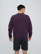 Buzo de felpa bordó, estilo relaxed, con cuello redondo y mangas raglán. Presenta puños y dobladillo acanalados, y una pequeña etiqueta con el logo de Umbro en el lateral inferior.
