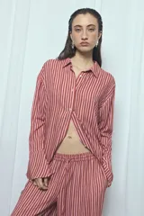 Camisa de viscosa con estampado de rayas verticales en tonos rosado y marrón, de corte oversize, con cuello camisero, cierre frontal de botones y mangas largas acampanadas.
