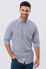 Camisa de lino a cuadros en tonos celeste y blanco, de manga larga, con cuello camisero, cierre frontal con botones y un bolsillo ojal en el pecho con detalle bordado.