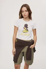 Remera blanca de manga corta, con estampa frontal de un pato de hule con turbante y labios pintados, acompañada de la frase "In all else fails, denial".