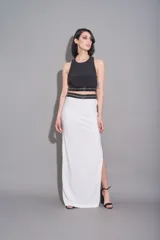 Conjunto de pollera larga blanca de crepe con tajo lateral, cintura bordada con lentejuelas y top negro con breteles y cintura bordados con lentejuelas.