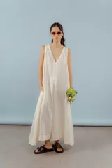 Vestido largo de lino color beige, con escote en V y diseño sin mangas de corte holgado y fluido.