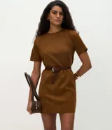Vestido corto de corte recto confeccionado en gamuza sintética color marrón. Presenta cuello redondo, mangas cortas y un acabado liso. Incluye un cinturón fino del mismo tono con hebilla metálica.