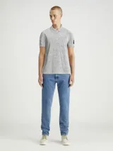 Chomba gris jaspeado de piqué de algodón peinado, con cuello clásico y tapeta de dos botones. Tiene mangas cortas, dobladillo con aberturas laterales y logo de Calvin Klein en la manga.