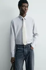 Corbata ancha confeccionada en tejido de seda con diseño de rayas diagonales en tonos beige y gris.