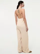 Mono color beige con escote halter, corte holgado, cinturón dorado y pantalones palazzo.