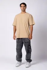 Remera de corte oversized en color marrón, confeccionada en tejido de algodón con textura de micropanal. Presenta cuello redondo con detalle de costura en forma de X y mangas cortas de estilo caído.