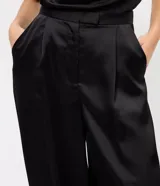 Pantalón aladín negro de satén, con diseño de caída amplia, cintura ajustada y botamanga con puño elástico.
