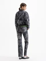 Pantalón de gabardina con corte jeanero y estampado damasco en tonos grises. Presenta bolsillos delanteros curvos con bolsillo relojero, bolsillos traseros plaqué y cierre frontal con broche metálico.