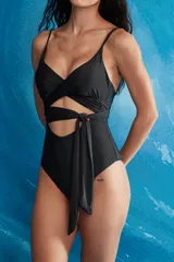 Trikini negro de una pieza con escote cruzado y lazo ajustable a la cintura que genera un corte cut-out en el abdomen. Posee delgados tirantes ajustables.