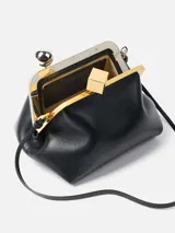 Cartera de cuero negro tipo sobre, con silueta abombada y marco metálico superior. Cuenta con broche de pinza decorado con una esfera plateada y un cubo dorado, correa fina desmontable y forro interior con tarjetero.