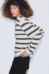 Jersey de punto con diseño a rayas horizontales en tonos crema, azul marino y marrón. Presenta cuello tipo polo en color celeste, cierre frontal con botones y puños y ruedo en tono celeste a juego.