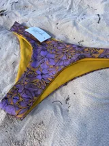 Bombacha de bikini vedetina con estampado de flores en tonos violeta y amarillo.