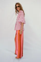 Camisa de corte oversize con estampado de rayas verticales rojas y blancas. Presenta cuello solapa, escote en pico y mangas largas abullonadas con puños elásticos.