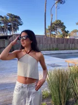 Top corto estilo halter color beige claro, con bordes ribeteados en costura de pespunte marrón oscuro.