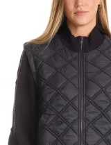 Campera combinada Current Air, con torso acolchado en diseño de rombos y mangas de tejido de punto grueso con diseño de ochos. Presenta cierre frontal metálico, cuello alto y puños y ruedo acanalados.