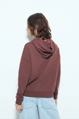 Canguro negro de calce relajado con capucha y cordones ajustables. Presenta un estampado gráfico frontal de un ojo con rayos de sol y la frase "STAY WEIRD".