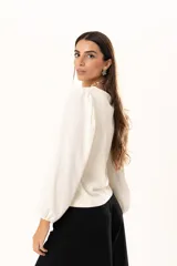 Blusa de cuello redondo con mangas largas tipo globo y puños elásticos. Presenta un diseño de textura combinada en el frente y las mangas.