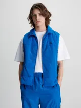 Chaleco acolchado azul eléctrico con cierre frontal, cuello alto y logo de Calvin Klein en el pecho.