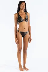 Bombacha de bikini con estampado animal print tipo cebra en tonos negro y beige, confeccionada en jacquard. Cuenta con un aro metálico decorativo en el lateral de la cadera.