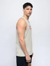 Musculosa sin mangas color beige claro con cuello redondo y estampa frontal con el logo de Umbro en rojo con patrón de líneas diagonales.