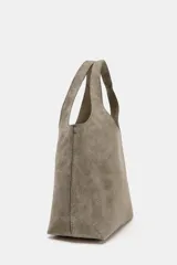 Bolso mini shopper de piel color gris topo, con doble asa de mano y asa bandolera extraíble. Cuenta con bolsillo interior con cremallera y cierre mediante botón imantado.