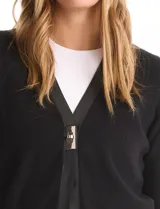 Cardigan de punto negro con escote en V, cierre frontal mediante herraje metálico y detalles de ribetes y bolsillos aplicados en cuero sintético.