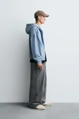 Sudadera con capucha y cierre de cremallera, de corte relajado (relaxed fit), confeccionada en algodón con interior afelpado. Presenta bolsillos frontales tipo canguro y acabados en rib. El tejido tiene un efecto lavado que le da un color negro desgastado.