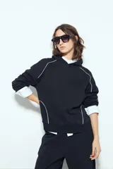 Canguro negro de silueta amplia con capucha integrada y detalles de líneas blancas que recorren el frente y las mangas.