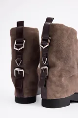 Bota de caña media confeccionada en cuero vacuno color marrón oscuro, con diseño de pliegues en la caña y suela de goma al tono con textura estriada.