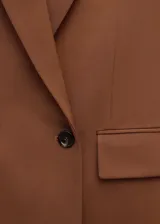 Blazer de corte sastrero color tostado, con diseño de doble botonadura, solapas clásicas y bolsillos laterales con solapa.