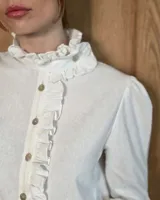 Camisa de manga larga con estampado de cuadros en tonos marrones y azules. Presenta cuello alto con volados, cierre frontal con botones y puños con volados.