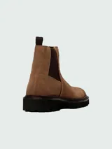 Botas tipo Chelsea Boss modelo Julyo-Cheb, confeccionadas en gamuza color tostado. Presentan paneles laterales elásticos en color marrón oscuro, tirador en el talón y suela de goma dentada de estilo track.