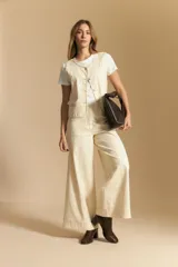 Chaleco negro de vestir con cuello solapa y cierre frontal de botones. Presenta costuras contrastantes blancas que definen el diseño y bolsillos delanteros. Se combina con una camisa blanca de manga larga.