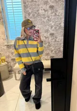 Sweater de punto a rayas horizontales amarillas y grises, con cuello polo y escote en V.