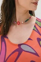 Vestido corto naranja con estampado abstracto en tonos morado, verde y blanco. Tiene corte recto, cuello redondo y mangas cortas.