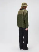 Campera tejido grueso y abrigado color verde militar, con forro de nylon interno, cuello estilo camisa en color negro y cierre frontal con botones. Cuenta con cuatro bolsillos delanteros con apliques en distintos tonos y texturas, y un parche bordado circular en el bolsillo superior izquierdo.