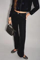 Pantalón de jean con acabado de terciopelo color azul marino, de tiro medio y corte sutilmente acampanado. Presenta cierre y botón frontal, con ruedo ancho como detalle.