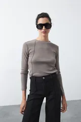 Remera de manga larga color gris topo, de calce entallado, con cuello a la base y costuras verticales que estilizan la silueta.