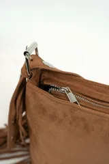 Cartera de gamuza color marrón con flecos en los laterales y tira con ojales metálicos.