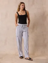 Pantalón cargo de lino a rayas verticales grises y blancas, marca Marissa Olivia. Pretina ancha elastizada con lazo de ajuste, bolsillos inclinados delanteros y bolsillos laterales con botón.