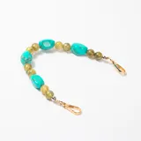 Accesorio decorativo para cartera compuesto por cuentas de resina en tonos turquesa y verde oliva, con ganchos metálicos dorados en los extremos.