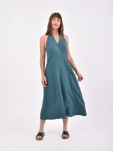 Vestido midi de color verde petróleo, con escote halter cruzado y espalda descubierta. Presenta un corte entallado en la cintura y falda con vuelo.