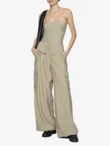 Pantalón color beige, de tiro medio, corte recto y largo hasta las rodillas. Presenta dos solapas que sobresalen de la pretina y dos bolsillos cargo a los costados de las piernas.